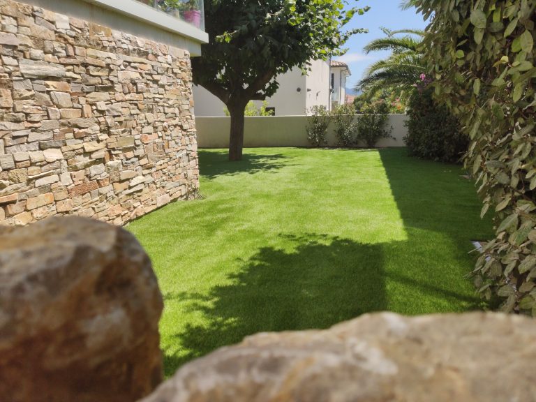 Jardin avec gazon synthétique installé par un paysagiste , illustrant une solution esthétique et pratique pour les espaces verts avec un entretien minimal.