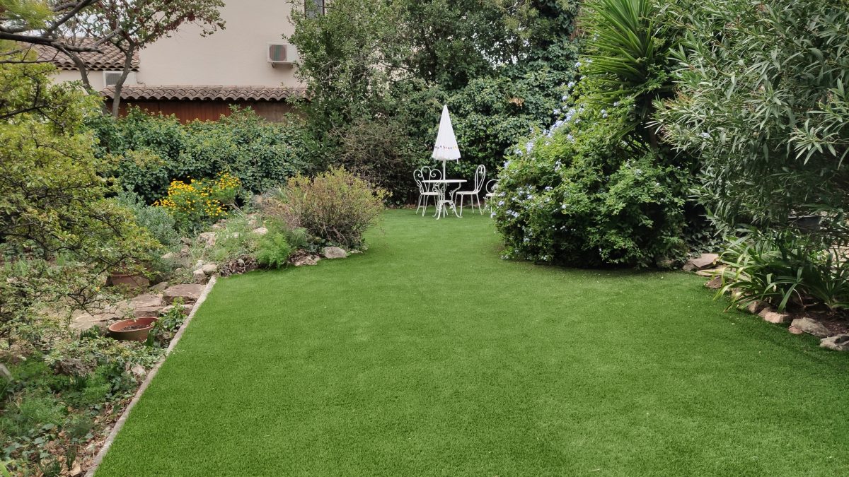 Terrasse en bois entourée de plantes méditerranéennes, illustrant une réalisation d'aménagement extérieur par un paysagiste local, combinant fonctionnalité et esthétique.