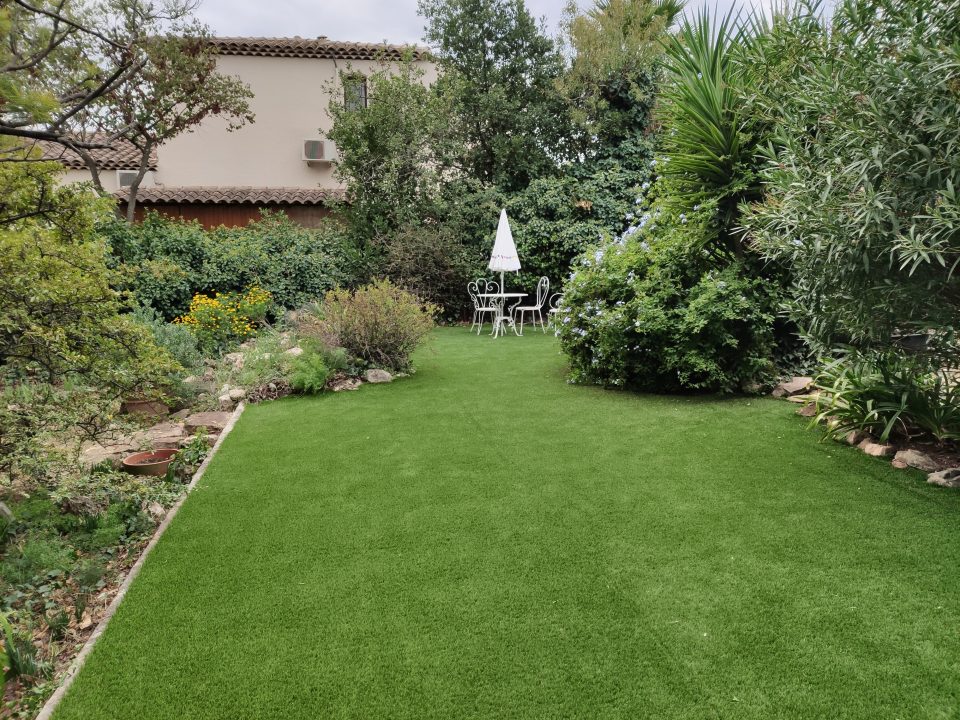 Terrasse en bois entourée de plantes méditerranéennes, illustrant une réalisation d'aménagement extérieur par un paysagiste local, combinant fonctionnalité et esthétique.